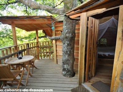 Cabane dans les arbres en Aquitaine, avec terrasse en bois et vue sur la nature.