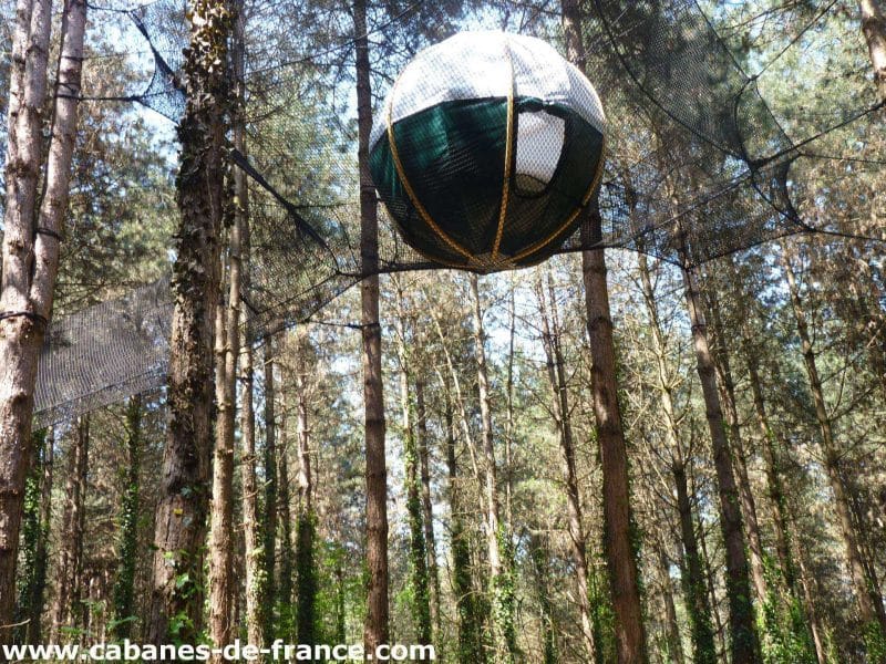 Hébergement insolite en Aquitaine : cabane en forme de boule suspendue dans les arbres.
