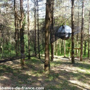 Hébergement insolite en Aquitaine : bulle suspendue dans les arbres, entourée de verdure.