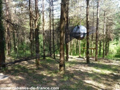 Hébergement insolite en Aquitaine : bulle suspendue dans les arbres, entourée de verdure.