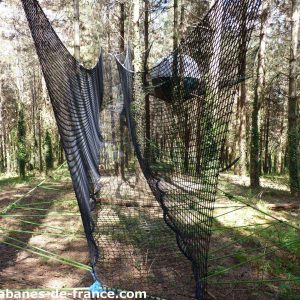 Hébergement insolite en Aquitaine : une cabane suspendue dans les arbres, entourée de verdure.