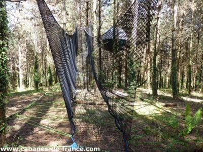 Hébergement insolite en Aquitaine : une cabane suspendue dans les arbres, entourée de verdure.