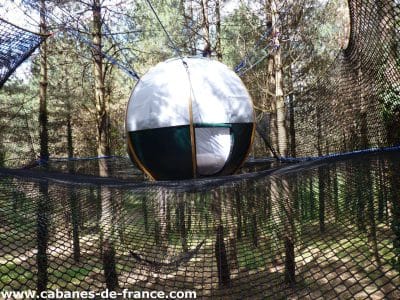 Hébergement insolite en Aquitaine : bulle suspendue dans les arbres, entourée de filets.