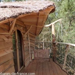 Cabane en bois perchée en Bretagne, avec terrasse en bois et vue sur la nature.