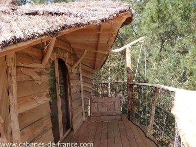 Cabane en bois perchée en Bretagne, avec terrasse en bois et vue sur la nature.