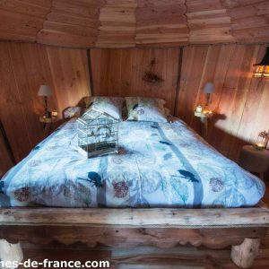 Cabane en bois à Grand-Est, lit douillet entouré de lanternes chaleureuses.