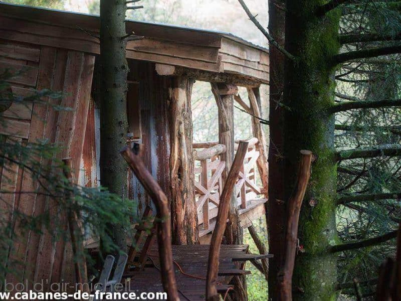 Cabane perchée en bois, nichée entre les arbres, offrant une vue paisible sur la nature.