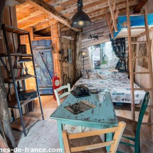 Cabane en bois dans les arbres, décor chaleureux et mobilier vintage coloré.