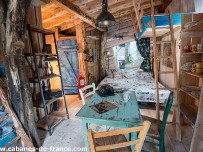 Cabane en bois dans les arbres, décor chaleureux et mobilier vintage coloré.