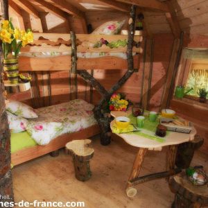 Cabane en bois cosy avec lit en mezzanine et décor floral, située en Grand-Est.