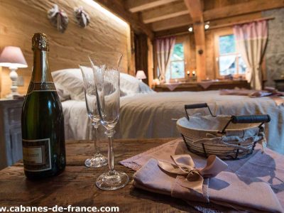 Cocon romantique en cabane, avec champagne et décor en bois chaleureux.