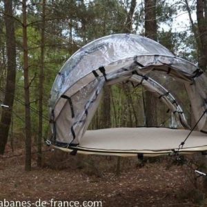 Hébergement insolite en Bretagne : tente suspendue transparente dans les arbres.