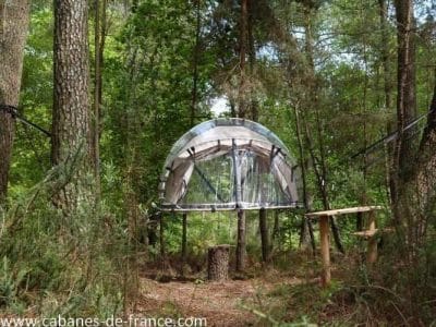Cabane suspendue en Bretagne, perchée entre les arbres, offrant une vue unique sur la nature.