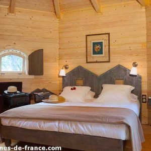 Cabane en bois dans le Languedoc-Roussillon, avec lit douillet et décor chaleureux.