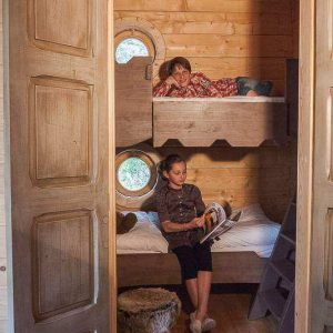 Cabane en bois dans le Languedoc-Roussillon, avec lits superposés et fenêtres rondes.