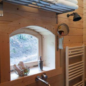 Cabane en bois dans le Languedoc-Roussillon, avec fenêtre arquée et serviettes blanches.