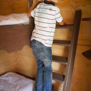 Cabane en bois dans le Languedoc-Roussillon, enfant grimpant une échelle intérieure.