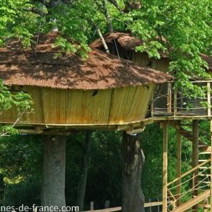 Cabane perchée en bois dans les arbres, entourée de verdure luxuriante en Bourgogne.