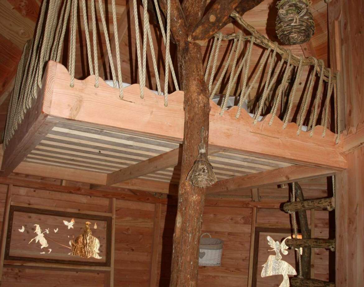 Cabane perchée en bois avec mezzanine et décor naturel, idéale pour un séjour unique.