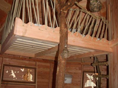 Cabane perchée en bois avec mezzanine et décor naturel, idéale pour un séjour unique.