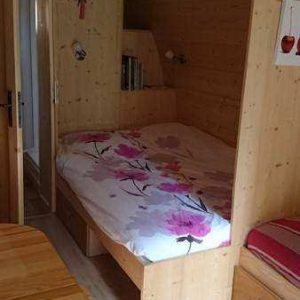Cabane en bois cosy avec lit douillet et décor floral, idéale pour un séjour unique.