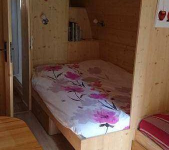 Cabane en bois cosy avec lit douillet et décor floral, idéale pour un séjour unique.