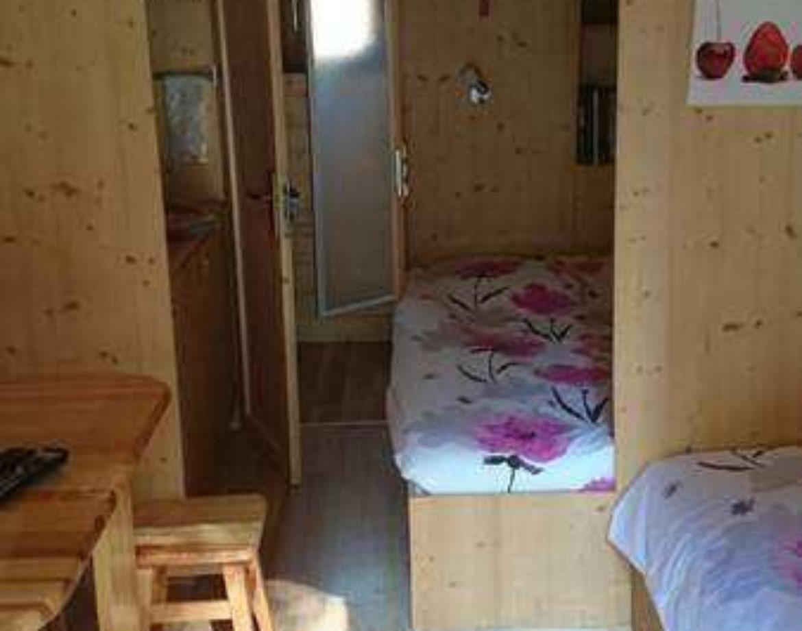 Cabane en bois cosy avec lits fleuris et coin repas chaleureux.