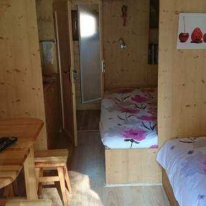 Cabane en bois cosy avec lits fleuris et coin repas chaleureux.