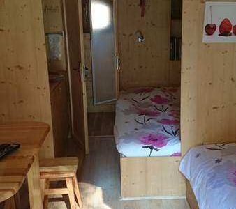 Cabane en bois cosy avec lits fleuris et coin repas chaleureux.