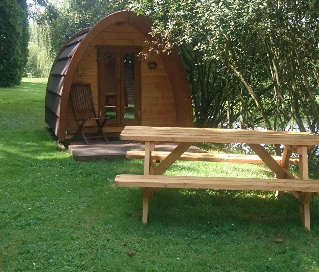 Cabane en bois ronde, entourée de verdure, avec une table de pique-nique.