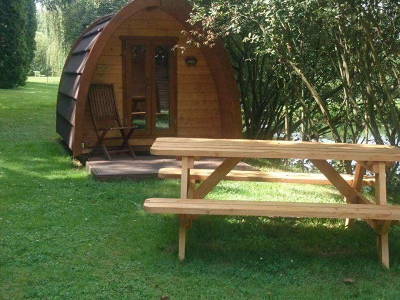 Cabane en bois ronde, entourée de verdure, avec une table de pique-nique.