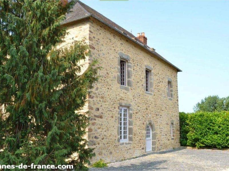 Charmante maison en pierre avec un jardin verdoyant et des fenêtres lumineuses.
