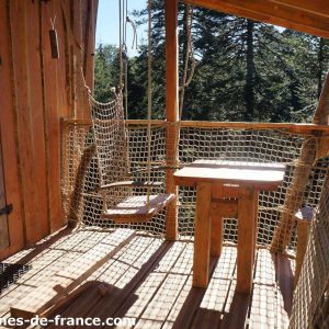 Cabane perchée en Auvergne avec une balançoire en filet et vue sur la forêt.