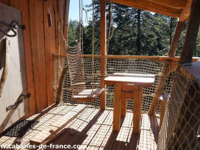 Cabane perchée en Auvergne avec une balançoire en filet et vue sur la forêt.