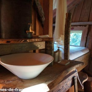 Cabane en bois en Auvergne avec lavabo en céramique et lit douillet.