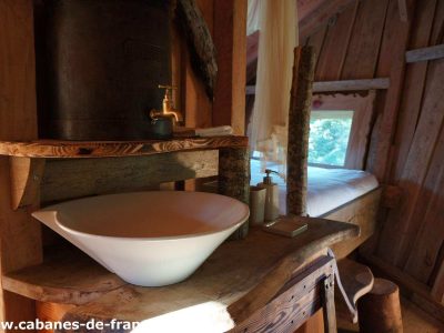 Cabane en bois en Auvergne avec lavabo en céramique et lit douillet.