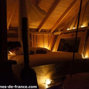 Cabane en bois cosy en Auvergne, éclairée par des lumières douces et chaleureuses.