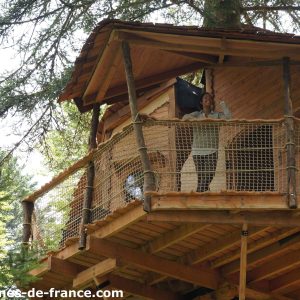 Cabane perchée dans les arbres en Auvergne, avec balcon en bois et vue sur la forêt.