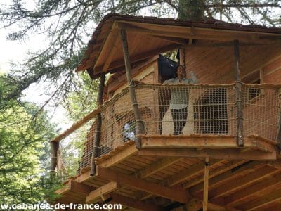 Cabane perchée dans les arbres en Auvergne, avec balcon en bois et vue sur la forêt.