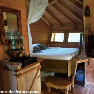 Cabane en bois en Auvergne, intérieur chaleureux avec lit douillet et décor naturel.