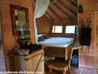 Cabane en bois en Auvergne, intérieur chaleureux avec lit douillet et décor naturel.