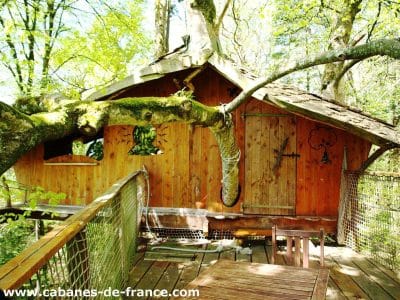 Cabane perchée en bois dans les arbres, entourée de verdure luxuriante.