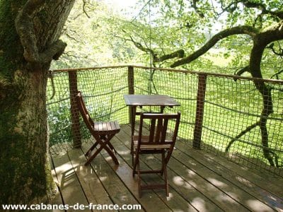 Cabane perchée dans un arbre en Bretagne, avec une terrasse en bois et vue sur la nature.