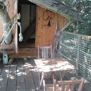 Cabane perchée en Bretagne avec terrasse en bois et vue sur la nature environnante.