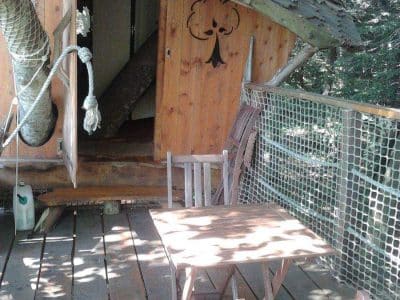 Cabane perchée en Bretagne avec terrasse en bois et vue sur la nature environnante.