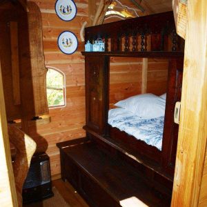 Cabane en bois en Bretagne, avec un lit douillet et des assiettes décoratives au mur.