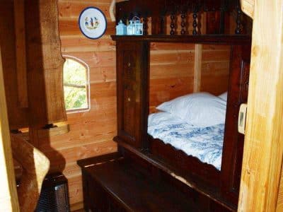 Cabane en bois en Bretagne, avec un lit douillet et des assiettes décoratives au mur.