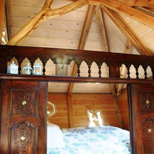 Cabane en bois en Bretagne avec un lit douillet et des lanternes décoratives.