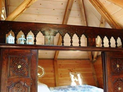 Cabane en bois en Bretagne avec un lit douillet et des lanternes décoratives.