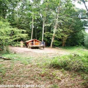 Cabane en bois perchée dans les arbres, entourée de verdure en Bretagne.
